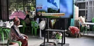 A displaced resident watches the news at an evacuation center in the Thai border province of Surin on December 11, 2025