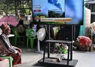 A displaced resident watches the news at an evacuation center in the Thai border province of Surin on December 11, 2025