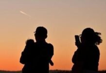 A family watches the last moments of twilight as the sun sets in Los Angeles, California, on March 18, 2026