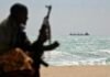 An armed Somali watches a Greek cargo ship anchored off NE Somalia in 2010