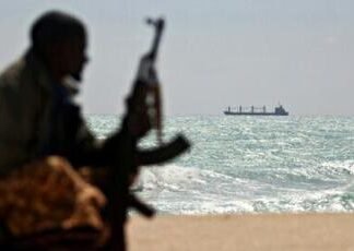 An armed Somali watches a Greek cargo ship anchored off NE Somalia in 2010